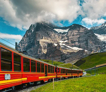 a train going through a valley with mountains in the background